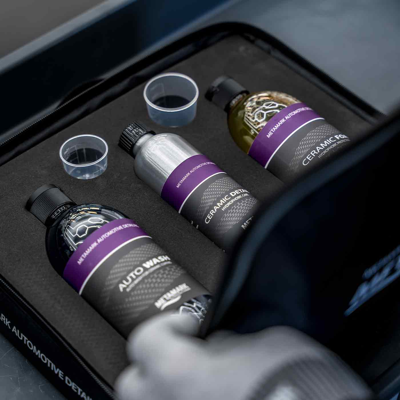 Automotive detailing products including bottles and cups in a black tray.