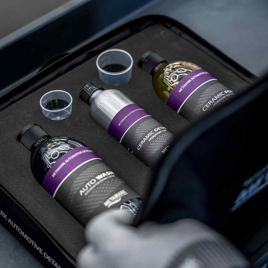 Automotive detailing products including bottles and cups in a black tray.